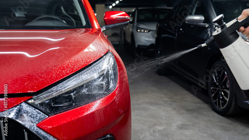 A man washes the headlights of a red car with a spray.  © Михаил Решетников