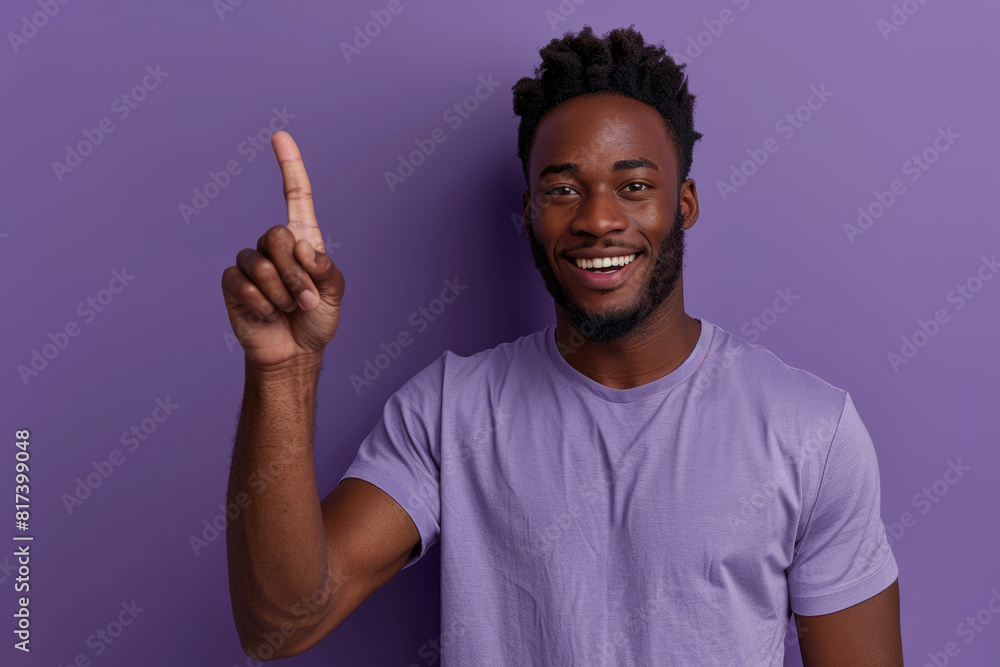 Photo of an excited black man wearing a casual t-shirt while pointing his index finger upwards on a purple background Photo of an excited black man wearing a casual t-shirt while pointing his index finger upwards on a purple background