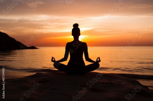 Sunset, beach and silhouette of a woman in a lotus pose while doing a yoga exercise by the sea. Peace, zen and shadow of a calm female doing meditation or pilates workout outdoor at dusk by the ocean  © alisaaa