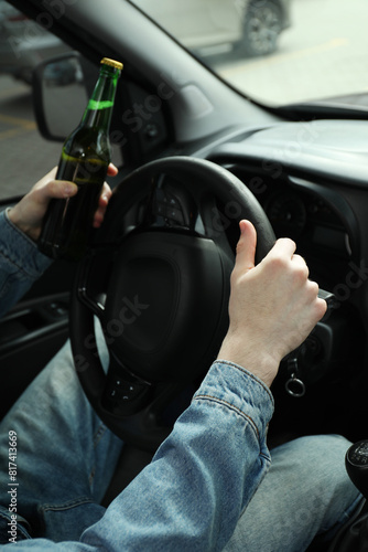 Obraz na plátně Man with bottle of beer driving car, closeup