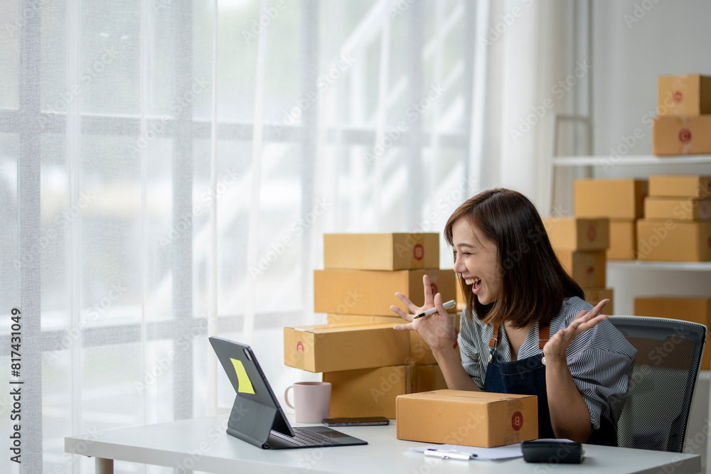 A woman is sitting at a desk with a laptop and a stack of boxes in front of her A woman is sitting at a desk with a laptop and a stack of boxes in front of her