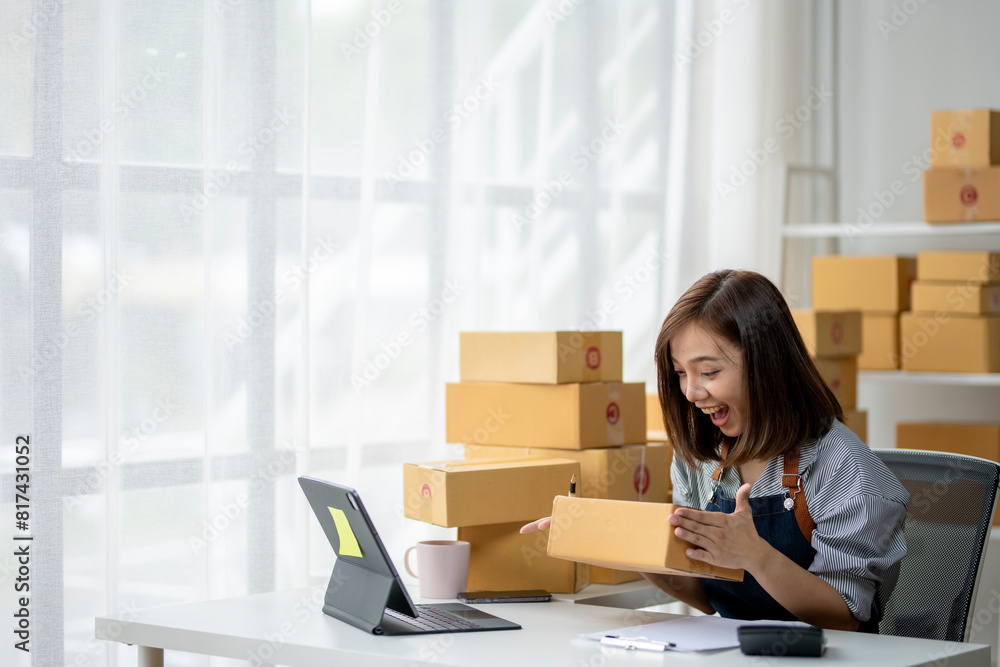 A woman is sitting at a desk with a laptop and a stack of boxes in front of her A woman is sitting at a desk with a laptop and a stack of boxes in front of her