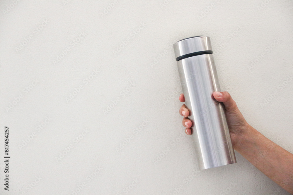 Close-up of woman's hand, holding a gray reusable stainless steel eco thermo water bottle with mockup, isolated on white background, aqua menthe. Plastic free. Zero waste. Close-up of woman's hand, holding a gray reusable stainless steel eco thermo water bottle with mockup, isolated on white background, aqua menthe. Plastic free. Zero waste.