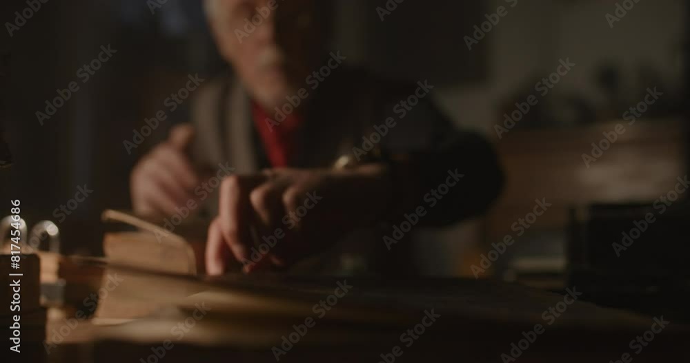 Old antique dealer picking something up from the desk. Old antique dealer picking something up from the desk.