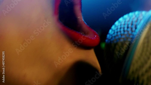 Closeup of sensuous singer wearing red lipstick seducing while singing. Female performer with microphone performing on stage in disco lights. She is having fun at event. photo