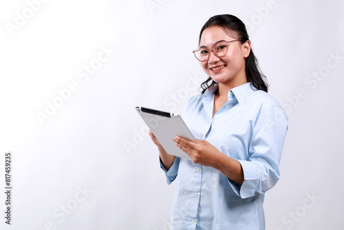 Portrait of young asian woman, company worker in glasses, smiling and holding digital tablet, standing over white background