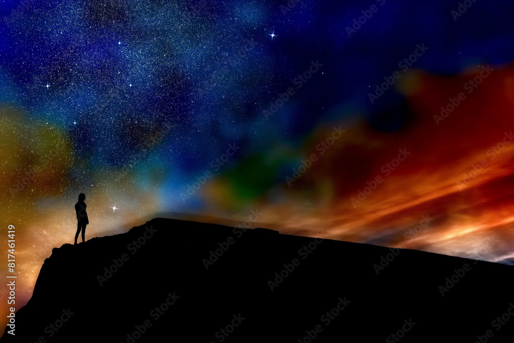 Fototapeta premium Silhouette of a person standing on top of a mountain with a starry night sky in the background