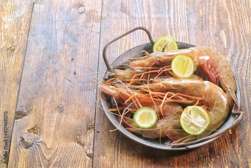 Shrimps. Close view and Selective Focus on Fresh Raw Shrimp or Prawn in round rustic tray with lime. On rustic wood Table.Litopenaeus vanname
 photo