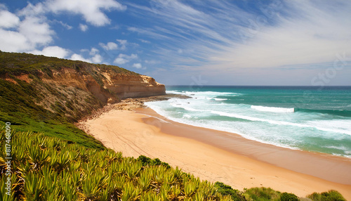 A beautiful beach with a cliff in the background. The sky is clear and the water is calm