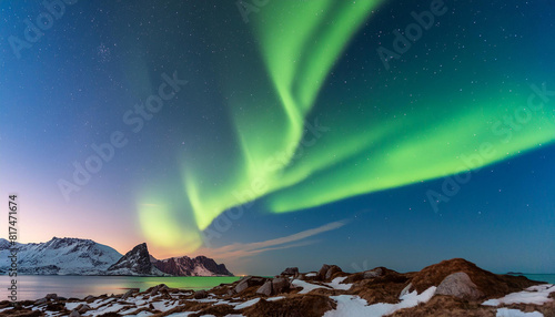 A mountain with a green aurora is in the background. There are two small houses in the foreground