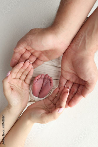 The palms of the father, the mother are holding the foot of the newborn baby in a white blanket. Feet of the newborn on the palms of the parents. Studio macro photo of a child's toes, heels and feet