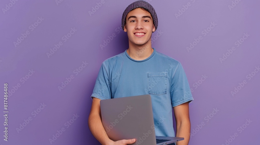 Young successful student or designer in blue t-shirt and beanie hat holding laptop while looking at camera against lavender background AI generated Young successful student or designer in blue t-shirt and beanie hat holding laptop while looking at camera against lavender background AI generated