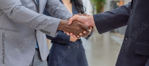 A diverse group of business professionals in suits shaking hands in agreement.