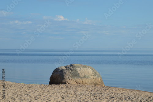 Large granite stone on shore of lake.
