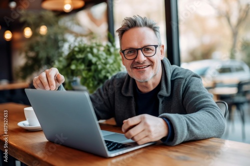 smiling man gesturing during video call through laptop at cafe
