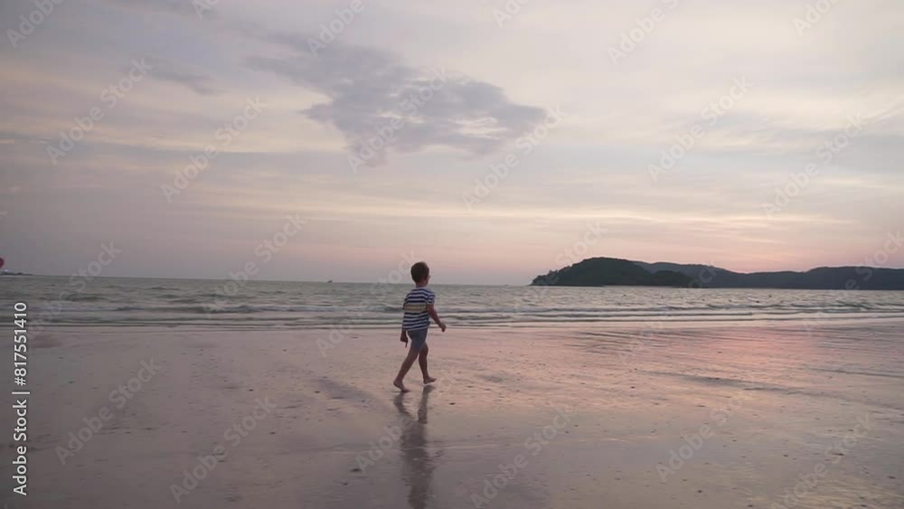 Little boy is running along a sand beach at sunset Little boy is running along a sand beach at sunset