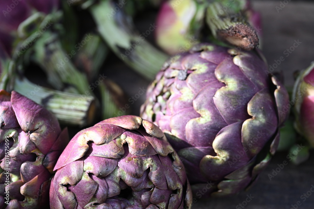 four artichokes next to one another with purple colored petals four artichokes next to one another with purple colored petals