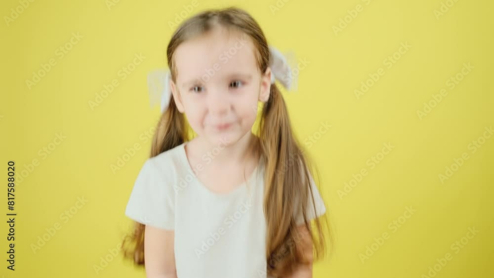 Portrait of a beautiful adorable little girl in a white t-shirt, saying yes, nodding her head at the camera on a yellow background Portrait of a beautiful adorable little girl in a white t-shirt, saying yes, nodding her head at the camera on a yellow background