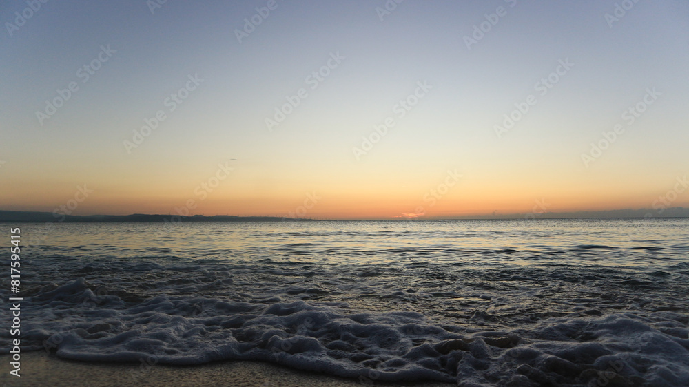 Obraz premium Sunset by the shore. Waves crashing into fine white sand during golden hour