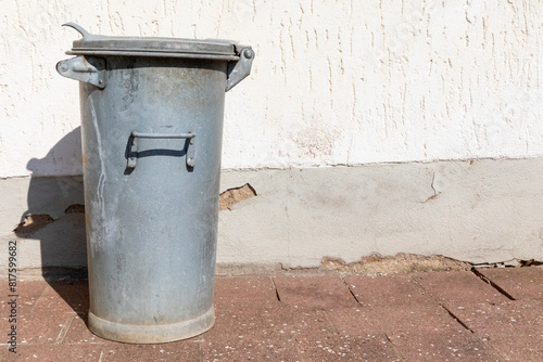 Mülltonne aus Metall vor einer Wand ,  eine geschlossene Abfalltonne am Haus. photo