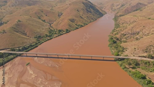 Top down view of car crossing huge bridge above Tsiribihina River in Madagascar countryside. Dirty river with yellow color after soil erosion. photo