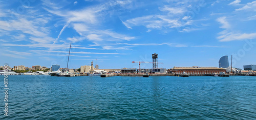 Obraz na plátně Wide angle view of shipping docks in the Mediterranean, with calm blue sea and blue sky with light clouds, construction cranes and loading and unloading equipment