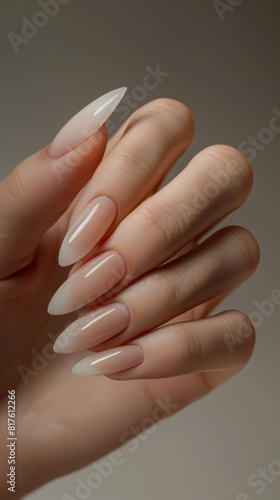 Photo of woman hand with manicure in beautiful fashion neutral colors. Pretty elegant acrylic nude cute gel polish stiletto nail manicure wear armor long nails for spa salon web advertising branding