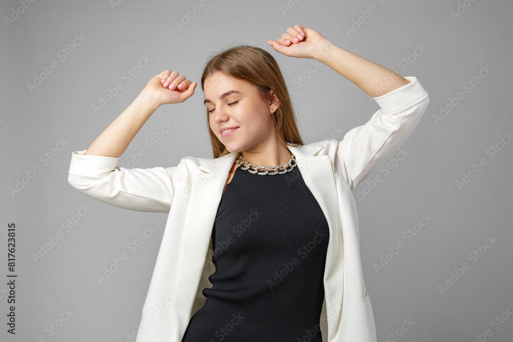 Confident Young Businesswoman Flexing Muscles in Smart Casual Attire Against Grey Background Confident Young Businesswoman Flexing Muscles in Smart Casual Attire Against Grey Background