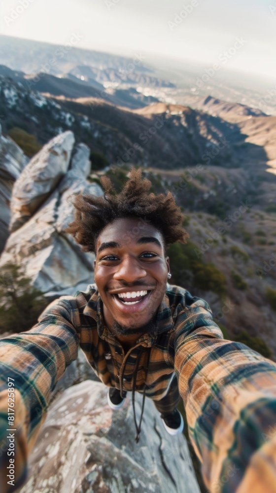 A man with a beard and a plaid shirt is smiling and taking a selfie. Concept of adventure and excitement, as the man is standing on a rocky mountain peak, capturing a moment of his journey A man with a beard and a plaid shirt is smiling and taking a selfie. Concept of adventure and excitement, as the man is standing on a rocky mountain peak, capturing a moment of his journey