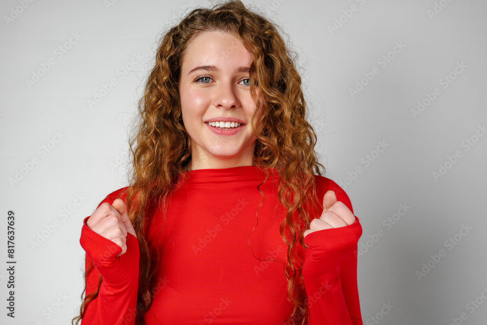 Excited Young Woman Celebrates Success With Raised Fists Against a Gray Background Excited Young Woman Celebrates Success With Raised Fists Against a Gray Background