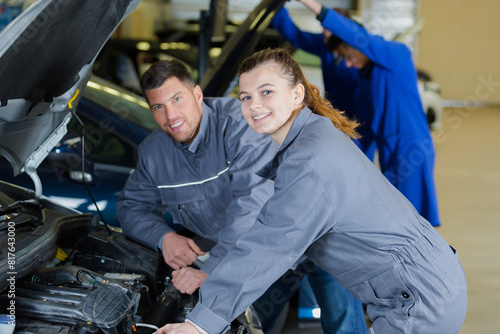 portrait of a young female trainee auto-mechanic with her supervisor