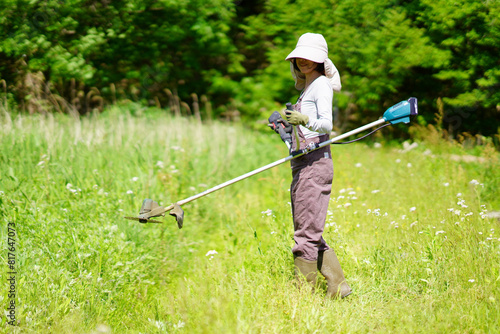 電動草刈り機で草刈りをする女性