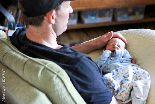 Father gently comforting his crying newborn at home photo