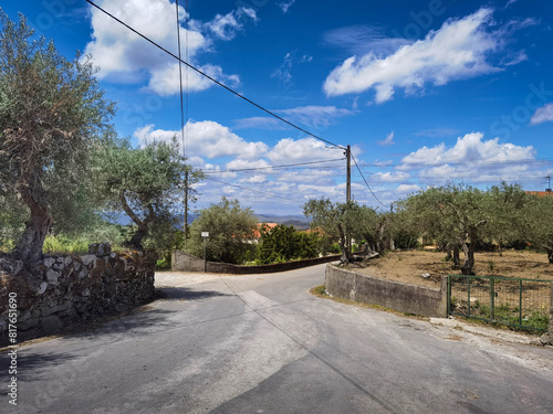 Em meio a uma aldeia um cruzamento em meio a oliveiras e muros antigos de pedra num dia ensolarado