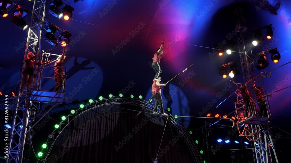 Circus performance of aerial acrobats-tightrope walkers on a tightrope ...