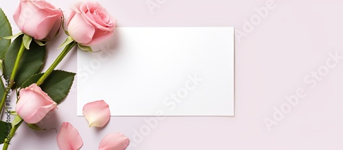 A copy space image featuring a pink rose frame and a blank card can be seen from a top view