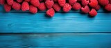 Close up copy space image of raspberries arranged on a vibrant blue wooden table