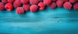 Close up copy space image of raspberries arranged on a vibrant blue wooden table