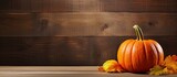 A pumpkin sits on a rustic wooden background with space for text This image represents the harvest season. Creative banner. Copyspace image