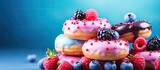 Glazed mini donuts with fresh raspberries and blueberries in an image with copy space