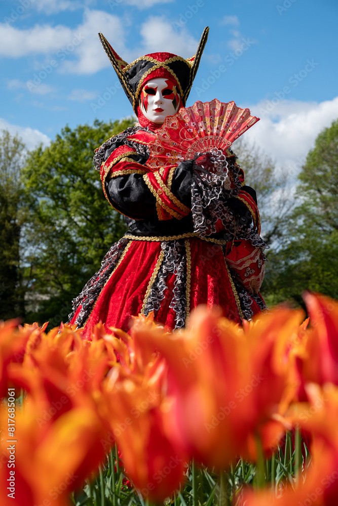 Fototapeta premium Venetian carnival character in a park with flowers