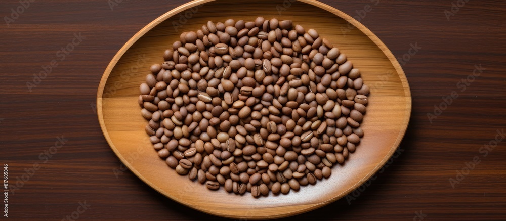 A top down view of a cluster of coffee seeds arranged on a bamboo plate surrounded by a wooden table with empty space for further items. Creative banner. Copyspace image A top down view of a cluster of coffee seeds arranged on a bamboo plate surrounded by a wooden table with empty space for further items. Creative banner. Copyspace image
