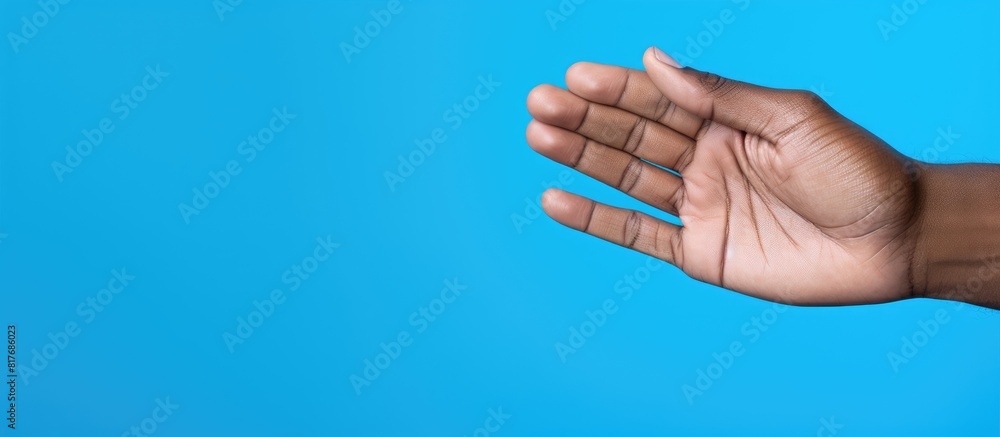 Fototapeta premium Copy space image of a man s left hand against a vibrant blue backdrop