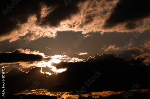 Beautiful contrast sky cloudscape in golden colors with sun through cumulonimbus on sunset
