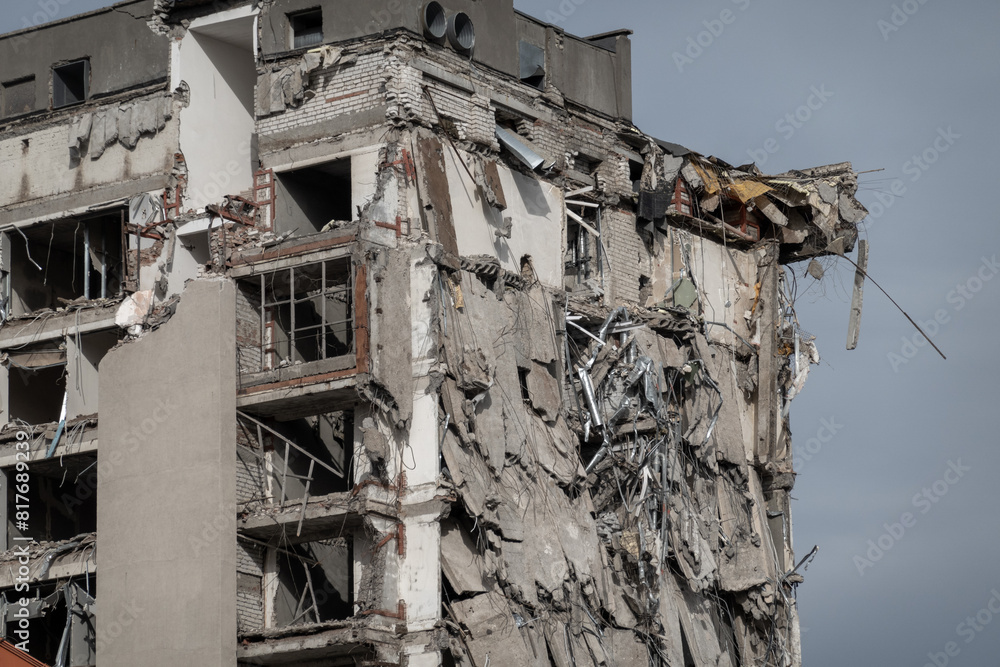 A high-rise building with extensive structural damage, showing exposed brick and debris, likely caused by a disaster. The structure looks unsafe and heavily deteriorated. A high-rise building with extensive structural damage, showing exposed brick and debris, likely caused by a disaster. The structure looks unsafe and heavily deteriorated.