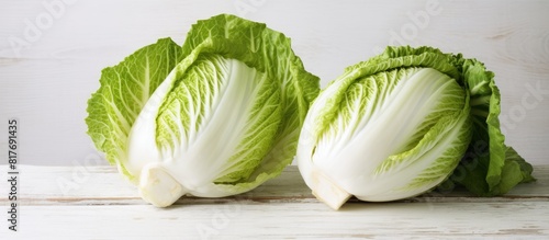 Table with a white wooden background showcasing fresh ripe Chinese cabbage both whole and cut Copy space image