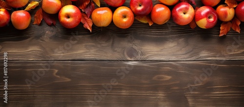 A top view shows a rustic wooden table adorned with ripe red apples and raw orange pumpkins offering plenty of copy space