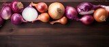 A mix of fresh raw onions both whole and sliced arranged on a wooden background Viewed from above with space for text or other images. Creative banner. Copyspace image