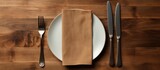 A top view of a table setting with an empty plate a knife a fork and a napkin providing ample copy space for customization