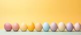 A copy space image of Easter eggs set against a pastel yellow background